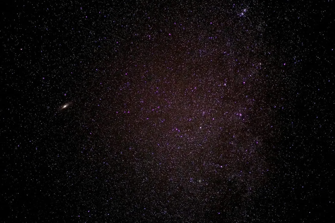 Cielo estrellado con numerosas estrellas brillantes en tonos púrpura y blanco.
