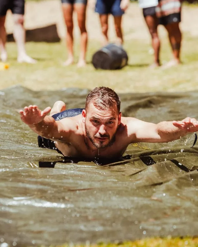 Un chico se lanza en plancha por el tobogán de agua ante el resto del grupo