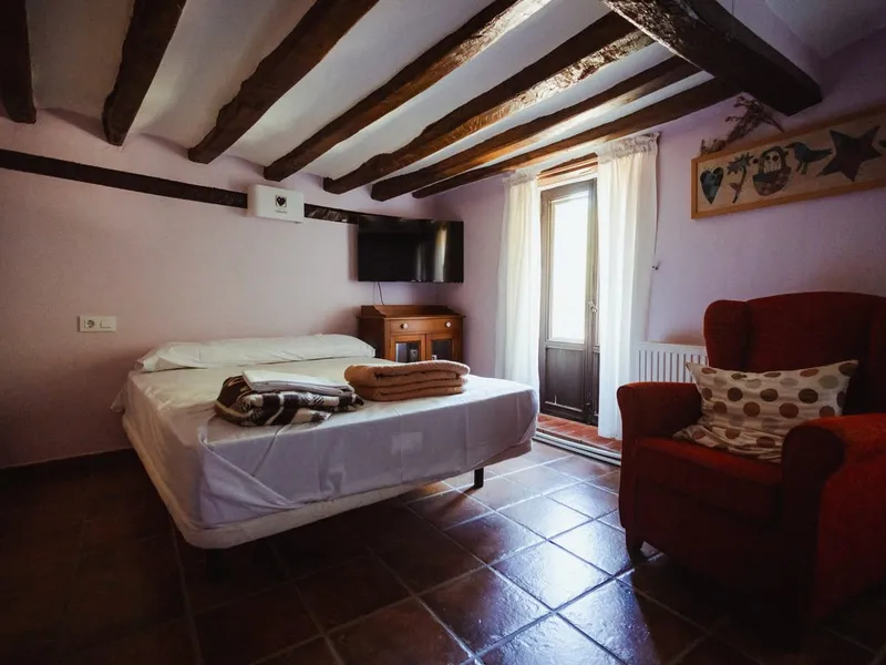 Habitación doble de una casa del pueblo, con vigas de madera y un sillón rojo