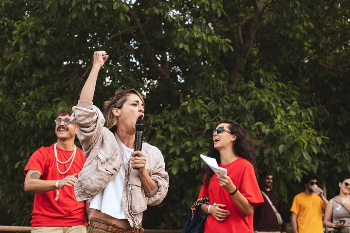 Dos animadoras con camiseta roja ríen y gritan con el micrófono durante una prueba