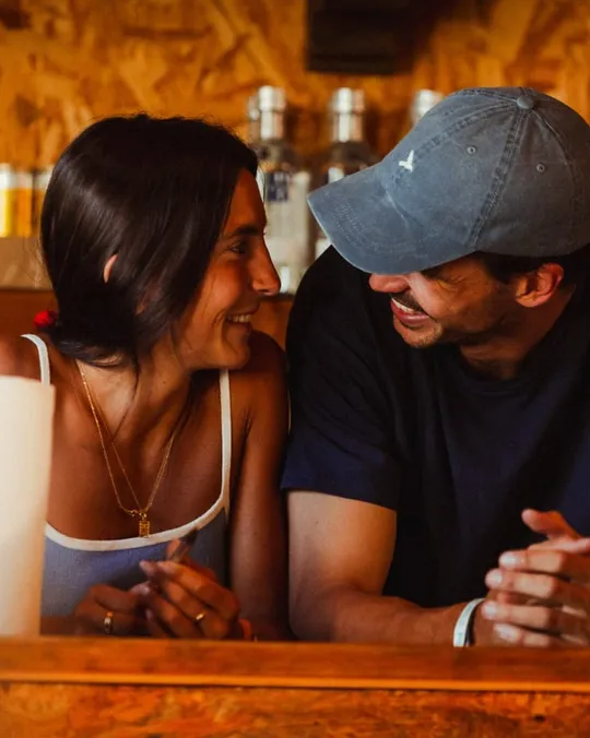 Una pareja charla apoyada en la barra de madera