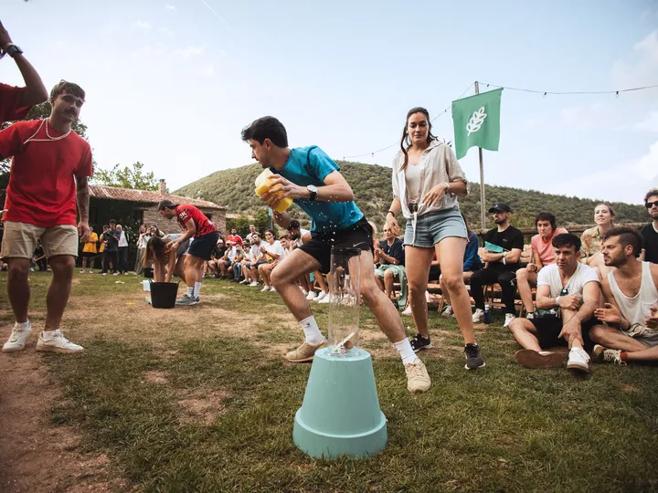 Un chico corre con un cubo entre los equipos y el público sentado en el césped