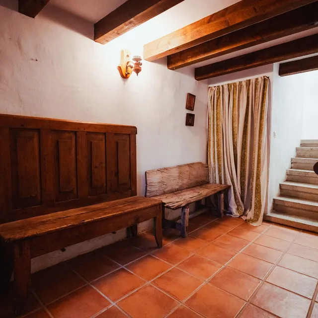 Recibidor de una casa rehabilitada del pueblo, con banco de madera y escalera