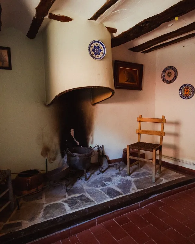 Salón de una casa del pueblo con chimenea de piedra y vigas de madera