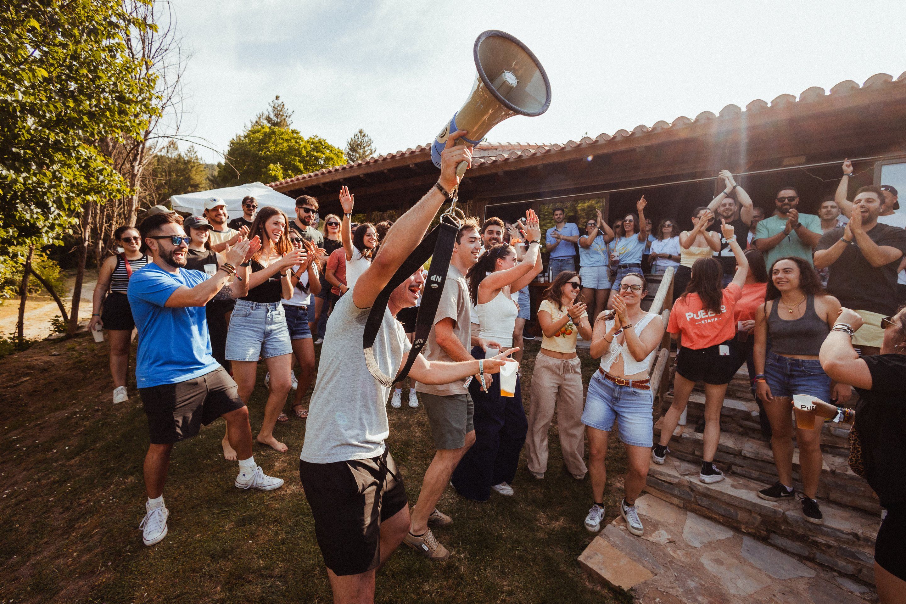 Un animador levanta el megáfono y la gente aplaude y baila delante de la terraza