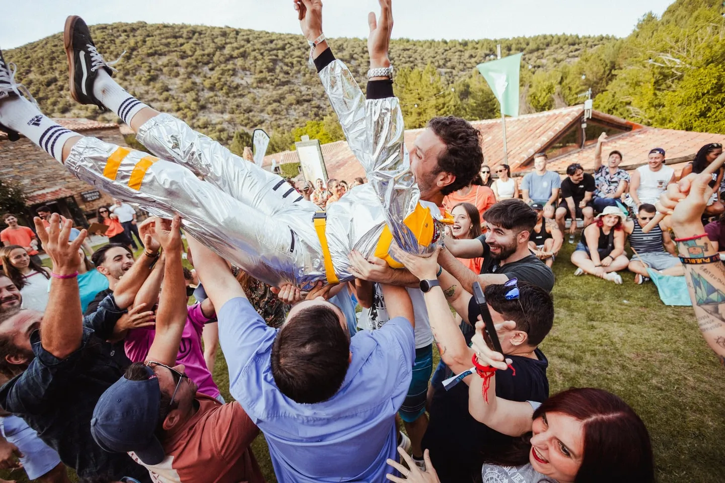 La gran final de la competición: el público mantea a un participante con mono plateado, a pleno día
