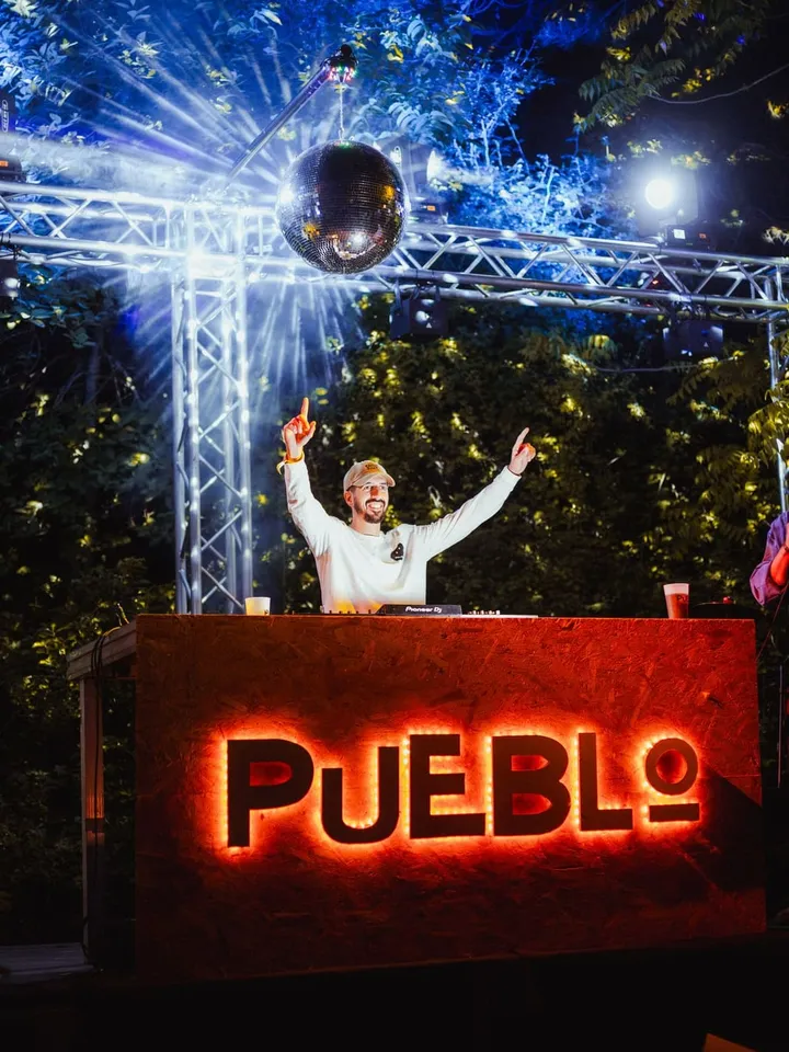 El DJ tras el rótulo luminoso de PUEBLO