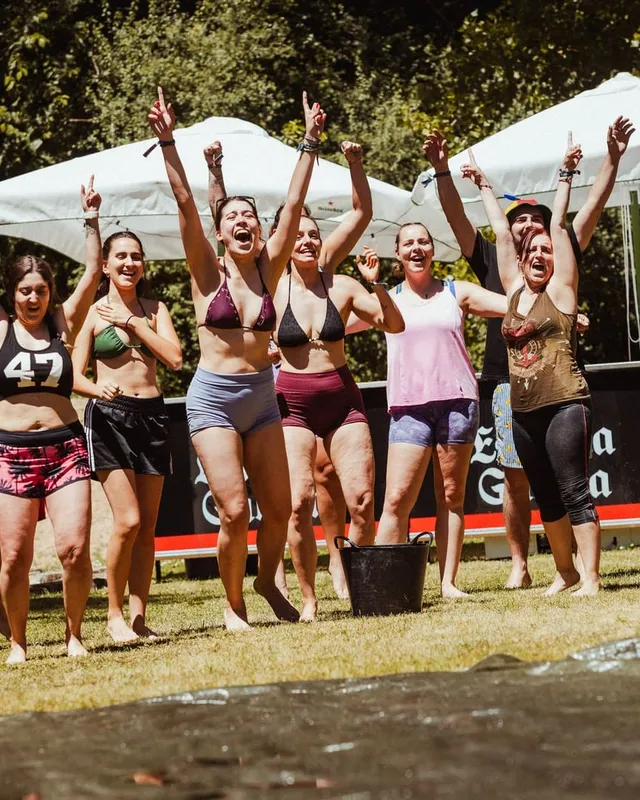 Un equipo celebra con los brazos en alto delante de las carpas, a pleno sol