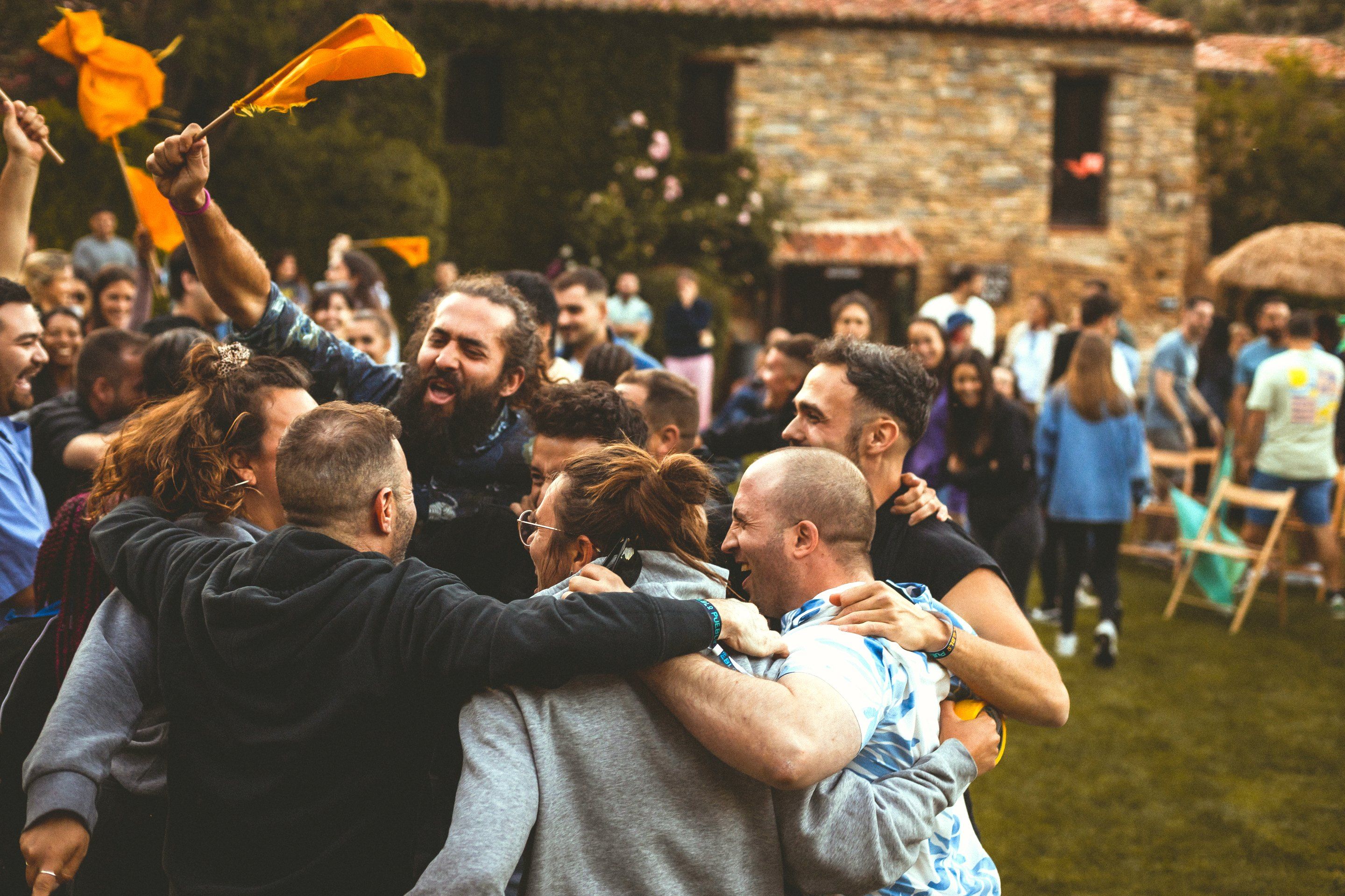 Abrazo de grupo de una Familia, con las banderas naranjas en alto, después de ganar una prueba