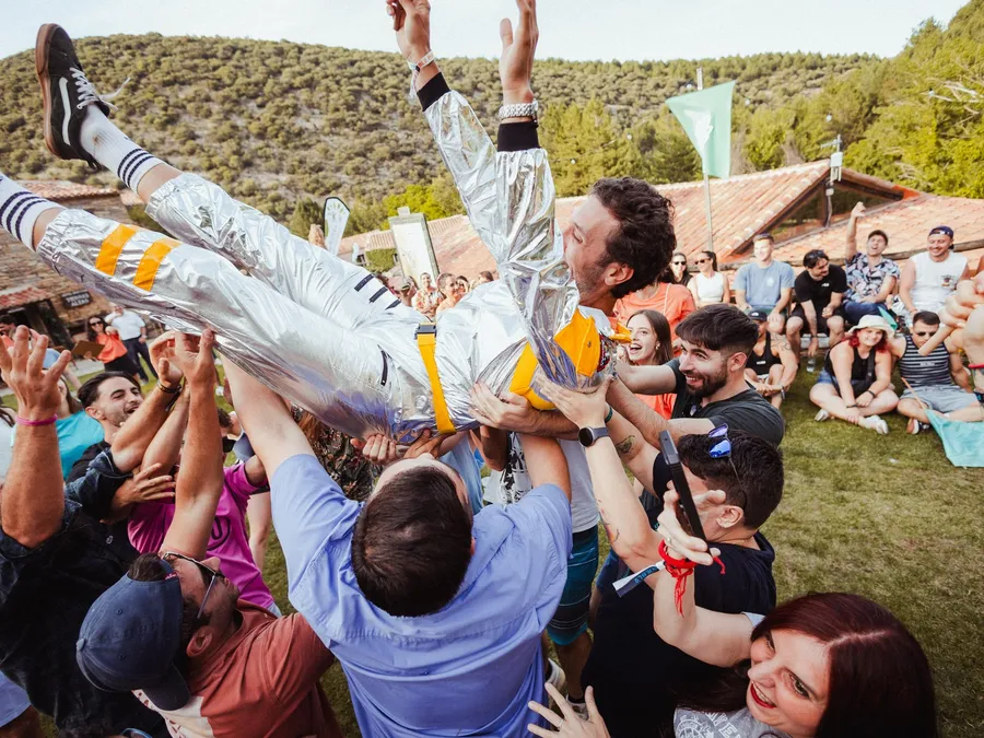 El público mantea a un chico vestido de astronauta en el césped de la plaza