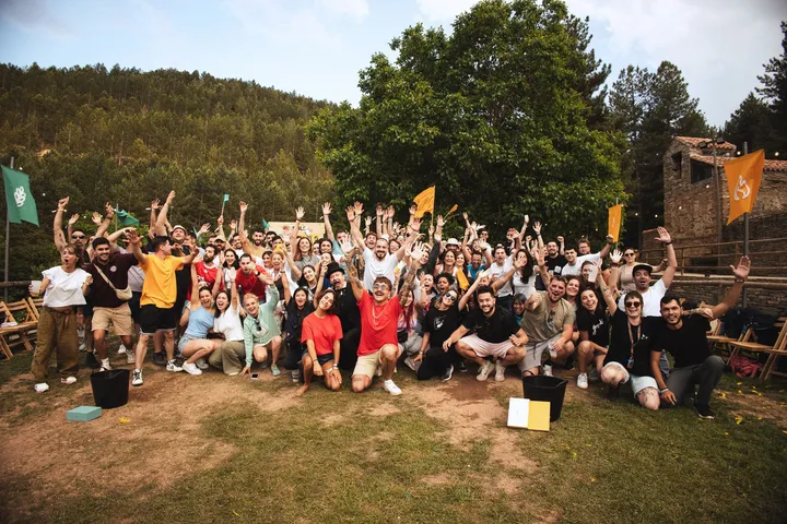 Foto de grupo de PUEBLO Fest Camp 2025 en Valdelavilla (Soria): todos con los brazos en alto y las banderas de las Familias