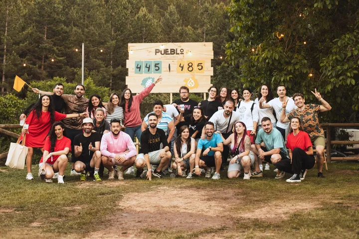 Foto de grupo frente al marcador final de PUEBLO 2025 con las banderas