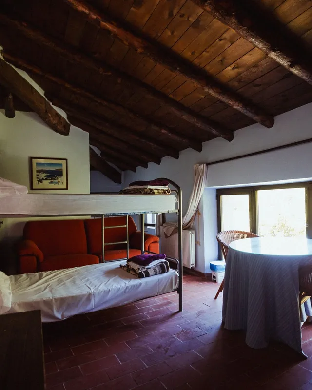 Habitación abuhardillada con litera, mesa redonda y ventana a la luz