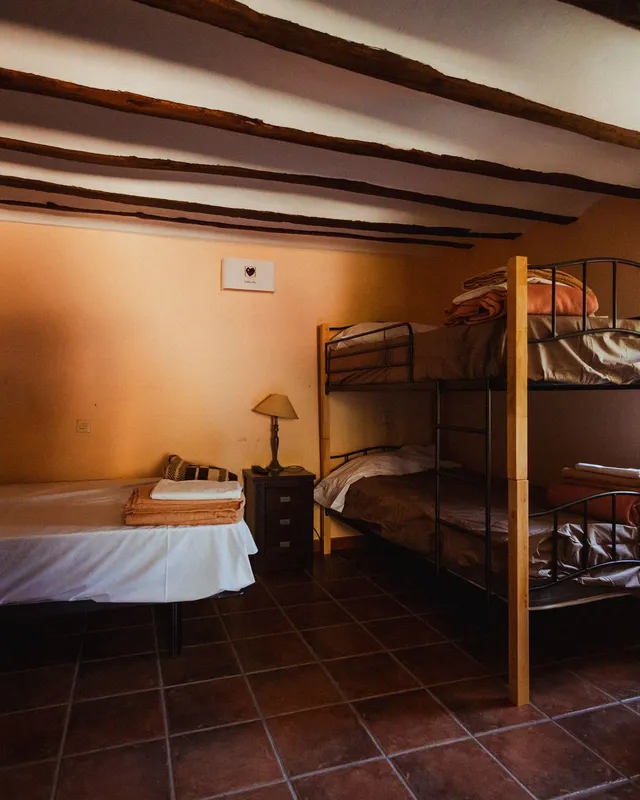 Habitación de una casa del pueblo con cama, litera de madera y paredes anaranjadas