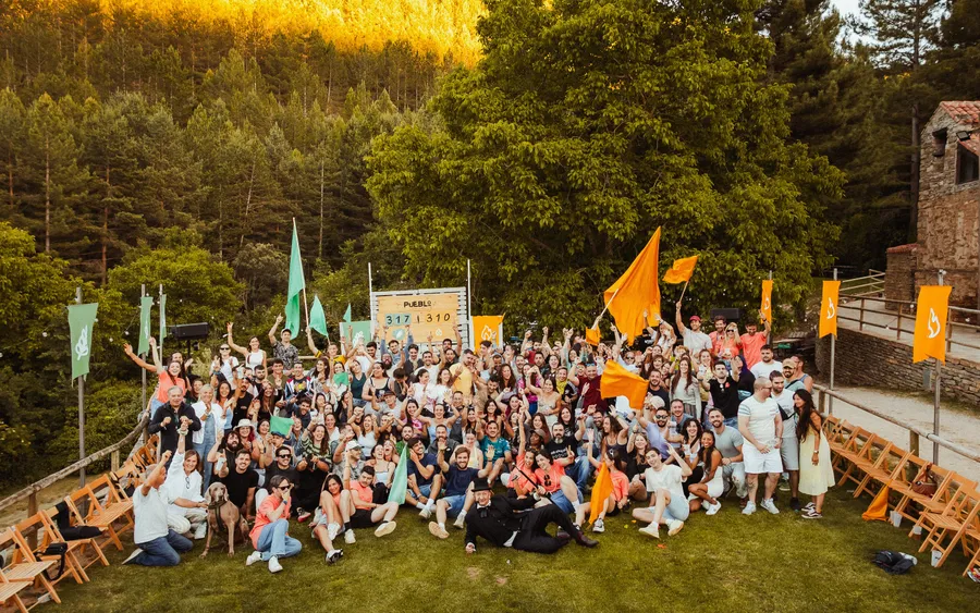Foto de grupo de PUEBLO 2026 en la pradera de Valdelavilla, con las banderas de las Familias