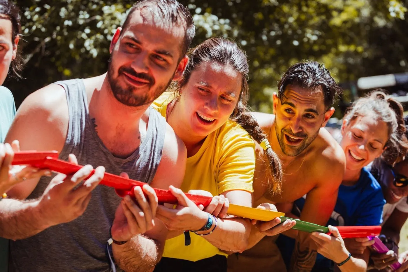 Cuatro personas de un mismo equipo pasan una bola por tubos de colores en un juego de equipo a pleno sol