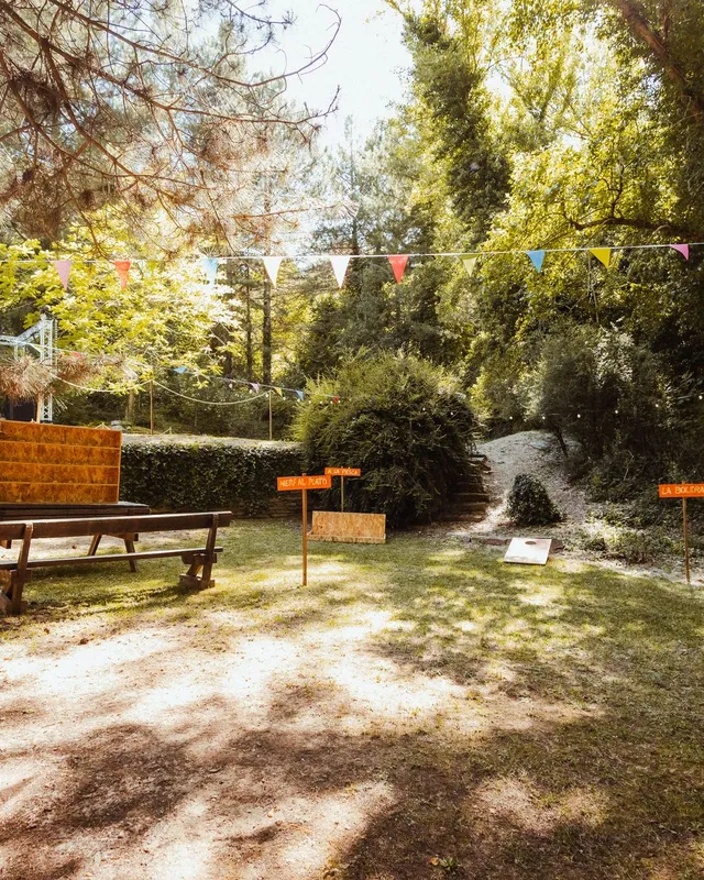 Rincón de césped con una mesa de picnic y banderines de colores entre los árboles