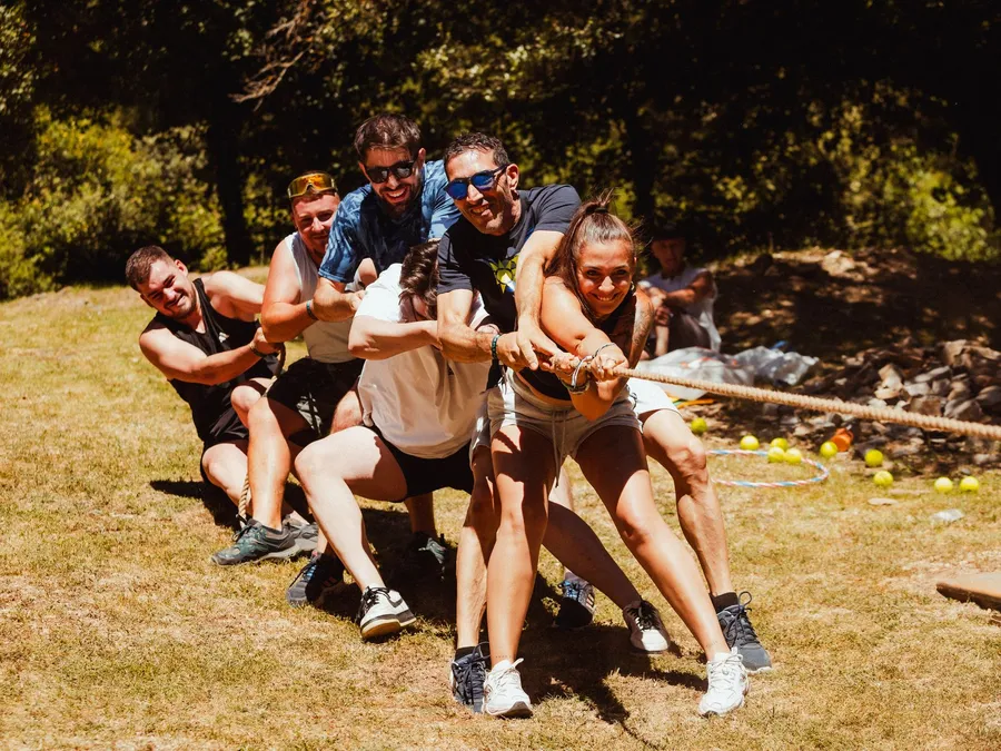 Un equipo tira de la cuerda con todas sus fuerzas, echado hacia atrás sobre el césped