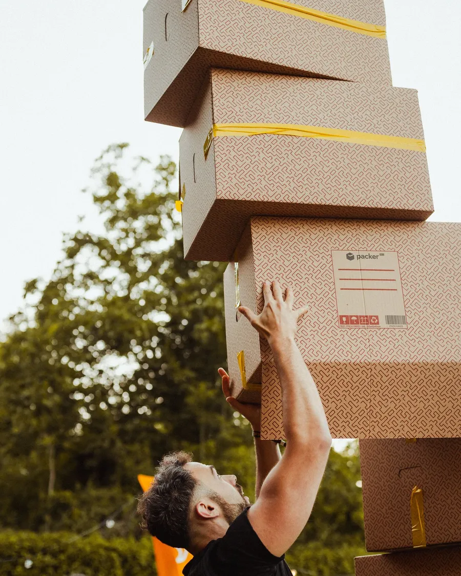 Un participante estira los brazos para sujetar una torre altísima de cajas de cartón