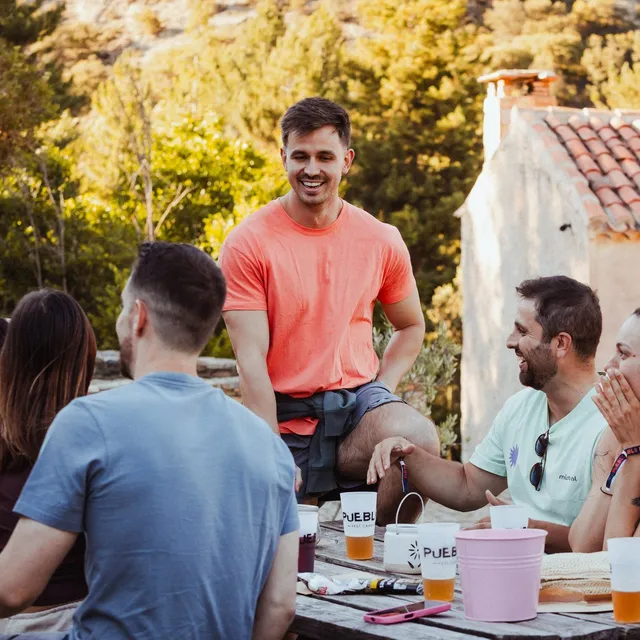 Un grupo recién conocido se ríe alrededor de una mesa de madera el primer día