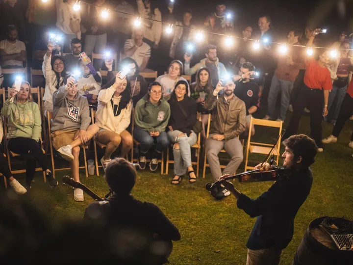 Concierto acústico de noche: el público ilumina con las linternas de los móviles bajo las guirnaldas