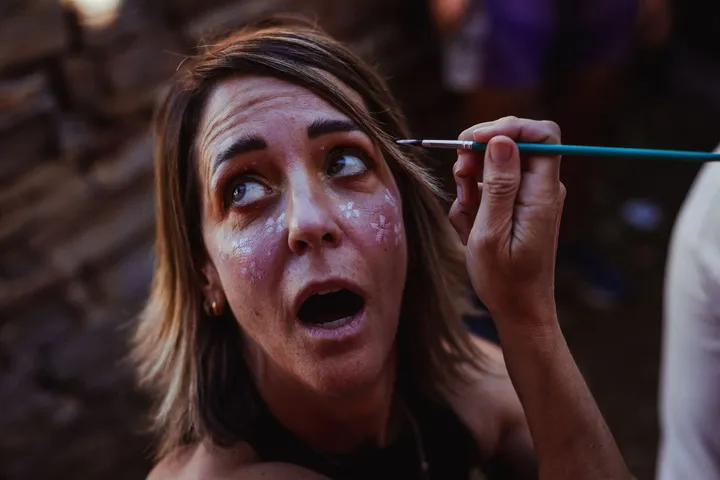 Una chica pone cara de sorpresa mientras le pintan la cara