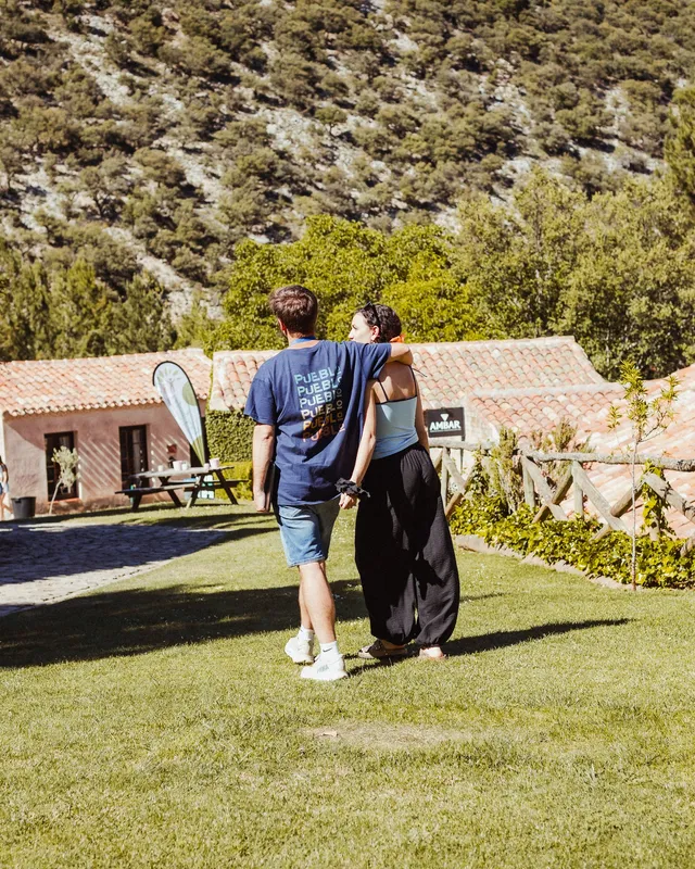 Pradera de césped junto a las casas de piedra, con el monte detrás