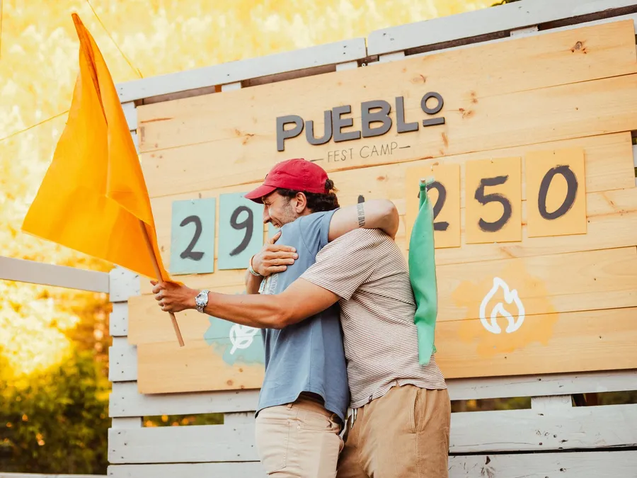 Dos chicos se abrazan delante del marcador, uno con la bandera naranja en la mano