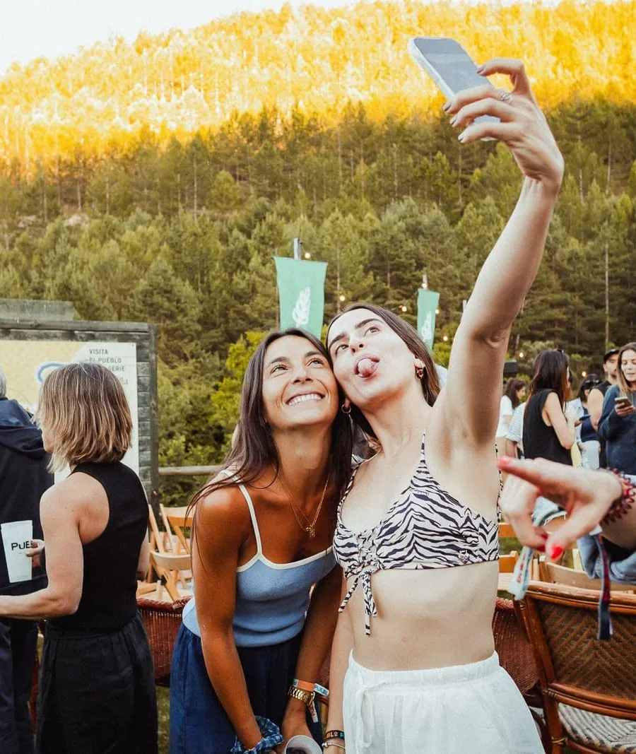 Dos amigas se hacen un selfie en la plaza, con el monte al fondo