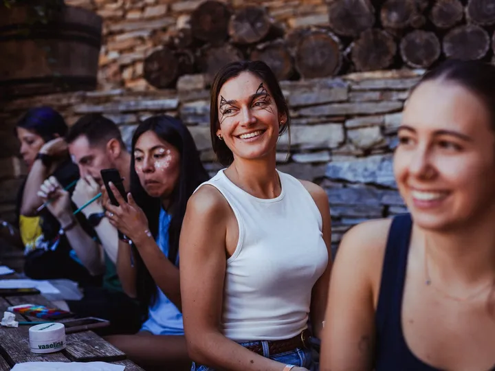Un grupo de amigas se ríe a carcajadas en un taller a la sombra de un muro de piedra