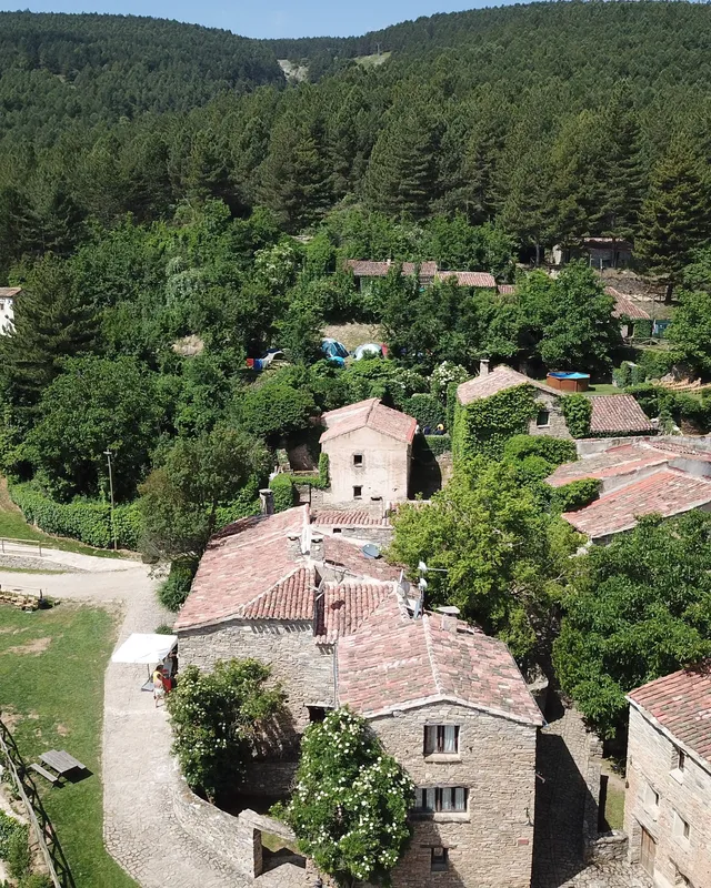 Vista aérea de Valdelavilla: las casas de piedra y tejados rojos del pueblo entre el bosque