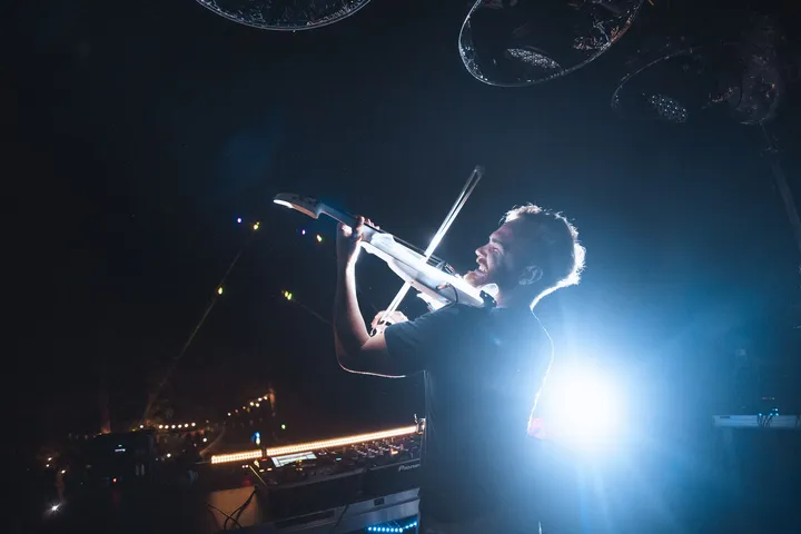 Un violinista toca a contraluz bajo un foco azul